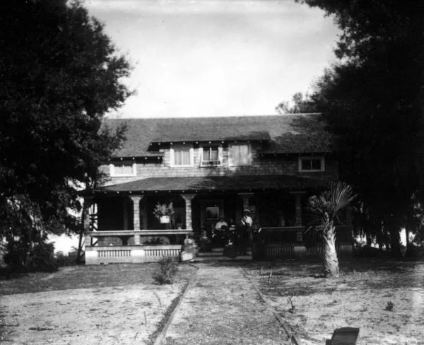 Historic photo of a Florida family sitting on the deep shaded front porch of their wood-frame home around 1900