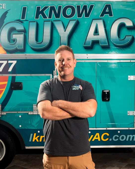 I Know A Guy AC technician standing in front of the branded turquoise truck