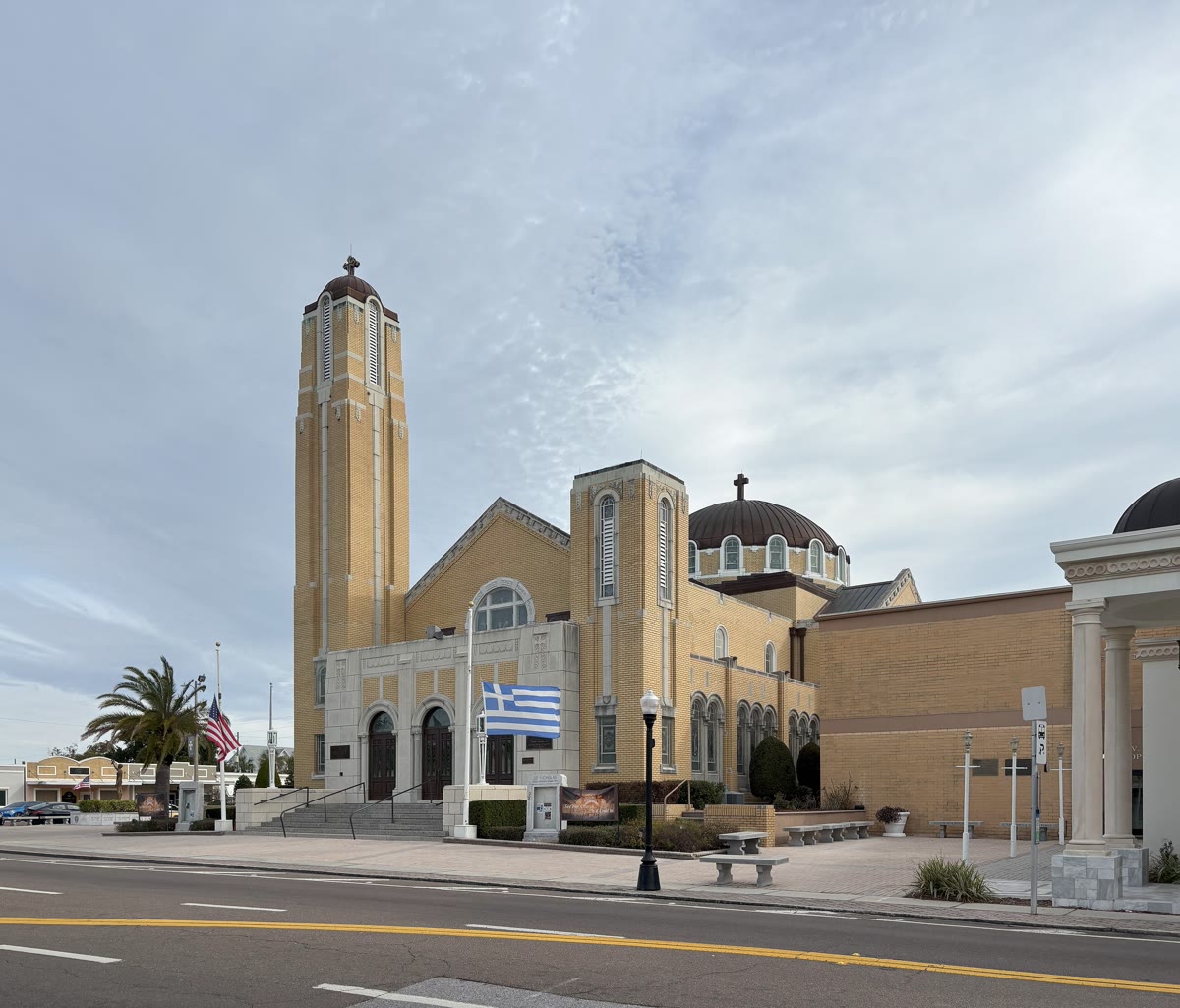A large cream-colored Byzantine Orthodox cathedral with a broad central dome and a bell tower, photographed against a blue sky in the present day.